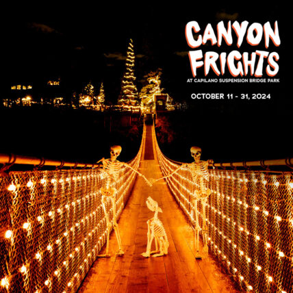 Skeletons cast eerie silhouettes against the night sky as they traverse the Capilano Suspension Bridge during Canyon Frights, with the bridge illuminated in haunting orange, adding a spooky ambiance to the Halloween festivities